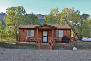 a log cabin with a porch and two chairs at Eycat Lodging Company Guest House in Wapiti