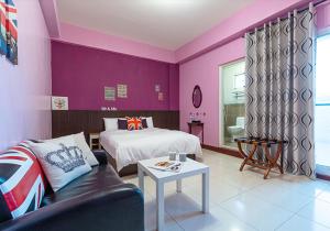 a bedroom with purple walls and a bed and a couch at Taitung Love Hostel in Taitung City