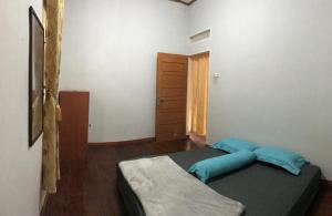 1 dormitorio con 1 cama con almohadas azules en Muda Raya Homestay, en Kotabaru