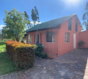 una piccola casa rossa con una siepe davanti di "Confortable Cabaña entre Paipa y Duitama" a Duitama