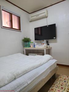 a bedroom with a bed and a flat screen tv at Chenal Motel in Daegu