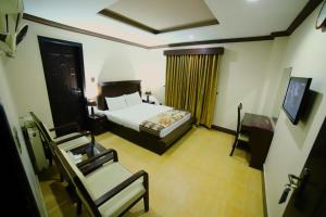 a bedroom with a large bed and a large window at Midtown Hotel Rawalpindi in Islamabad