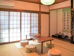 a room with a table and stools and windows at Guesthouse Hakuka in Kanazawa