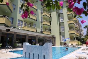 a hotel with a swimming pool in front of a building at Almera Park Apart Hotel in Alanya