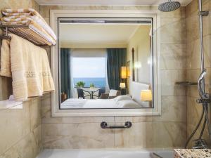 un bagno con vasca e un grande specchio di Alexander The Great Beach Hotel a Paphos