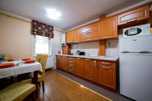 a kitchen with wooden cabinets and a white refrigerator at Lilla Apartments in Odorheiu Secuiesc