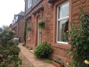 a brick house with a sidewalk next to a window at Lauren House in Dumfries