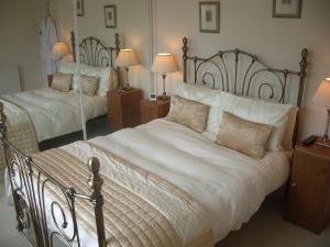 um quarto com 2 camas com lençóis brancos e almofadas em Lauren House em Dumfries