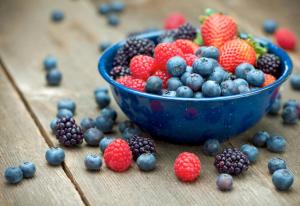 a blue bowl of berries on a wooden table at Agriturismo Al Palaz in Prata Camportaccio