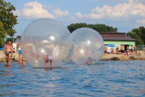 dos niños están jugando en dos grandes bolas de plástico en el agua en Holiday flat, Stepnica, en Stepnica