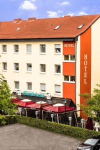 un hôtel avec des tables et des parasols devant lui dans l'établissement Hotel Gambrinus Arnsberg, à Arnsberg
