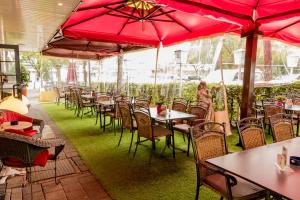 un restaurante con mesas y sillas con sombrillas rojas en Hotel Gambrinus Arnsberg, en Arnsberg