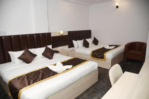una habitación de hotel con 2 camas y una silla en Clarissa Resort Goa, en Saligao