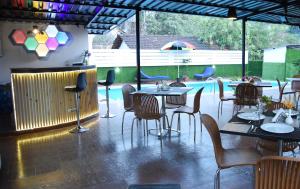 un restaurante con mesas y sillas y una piscina en Clarissa Resort Goa, en Saligao