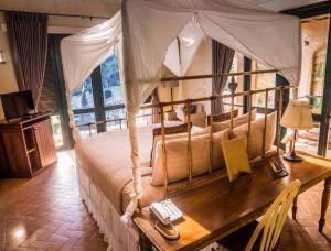 - une chambre avec un lit à baldaquin et une table en bois dans l'établissement La Toscana, à Suan Phueng