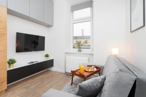 a living room with a couch and a tv at Studio Cracow Wawrzyńca by Renters in Krakow
