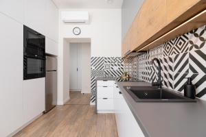a kitchen with a sink and a black and white patterned wall at Studio Cracow Wawrzyńca by Renters in Krakow