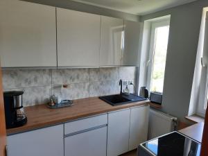 eine Küche mit weißen Schränken und einer Spüle und einem Fenster in der Unterkunft Holiday Home Sieroslaw near Baltic Sea in Sierosław