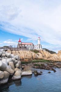 a lighthouse sitting on top of a rocky island at Kenny Stay Busan Gijang in Busan
