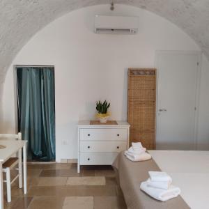 a bedroom with a bed and a dresser and a table at Liama sull'Aia in Marina di Pescoluse