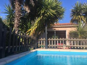 a swimming pool in front of a fence with palm trees at Charmant studio avec piscine . in Afa