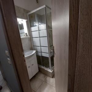 uma casa de banho com uma cabina de duche em vidro e um lavatório. em Yolanda Studios em Pireu