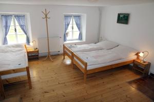 a bedroom with two beds and two windows at Penzion Mauritz in Nová Pec