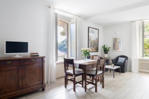comedor con mesa, sillas y TV en Villa Maria Apartments, en Cannobio
