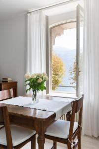 una mesa de comedor con un jarrón de flores. en Villa Maria Apartments en Cannobio