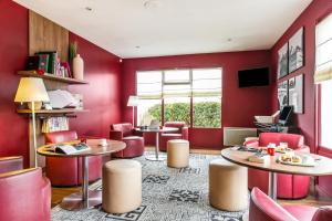 ein Restaurant mit roten Wänden, Tischen und Stühlen in der Unterkunft Campanile Château-Thierry in Château-Thierry