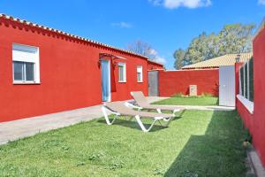 een bank op het gras naast een rood gebouw bij Chalet Brisa Veraniega in Conil de la Frontera