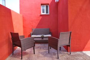 een patio met 3 stoelen en een tafel en een rode muur bij Chalet Brisa Veraniega in Conil de la Frontera