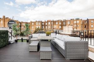 a patio with a couch and tables on a roof at Superb 3 Bed/Bath Luxury + Ibiza Roof Terrace in London