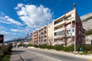 a building on a street with mountains in the background at Sea View Apartment Michelle near Osejava in Makarska