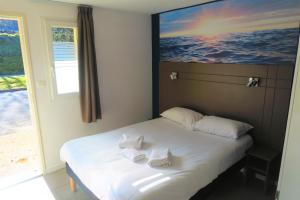 a bedroom with a bed with two towels on it at Hôtel Confort Le Moulin Rouge in Terrasson-Lavilledieu