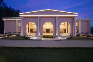 une grande maison blanche avec colonnes et lumières dans l'établissement Clarks Resort Birgunj, à Bīrganj