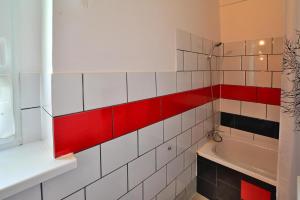 a bathroom with red and white tile on the wall at Comfortable 2 person holiday apartment in the countryside Drezno in Stare Wierzchowo