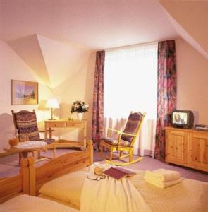 a bedroom with a bed and chairs and a window at Hotel Fröbelhof in Bad Liebenstein