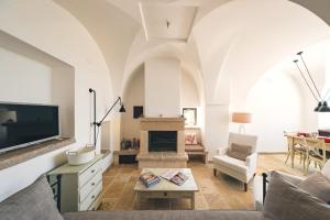 ein Wohnzimmer mit einem TV und einem Kamin in der Unterkunft HelloAPULIA - Masseria Minetta - Infinity Saltwater Pool & Scenic View in Cisternino