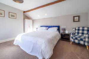 a bedroom with a large white bed and a chair at The Piggery in Chappel