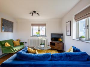 a living room with a blue couch and a tv at Chestnut Cottage in Winchcombe