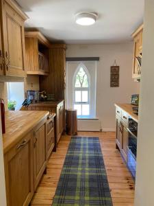 a large kitchen with wooden cabinets and a window at Rathjarney Gatelodge in Wexford