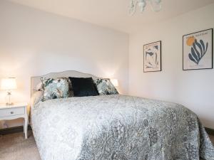 a bedroom with a bed and a night stand with a lamp at Chestnut Cottage in Winchcombe
