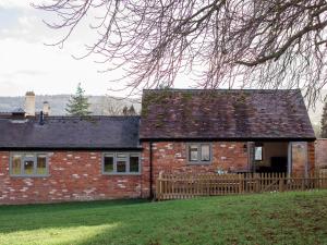 a red brick house with a wooden fence at Chestnut Cottage in Winchcombe