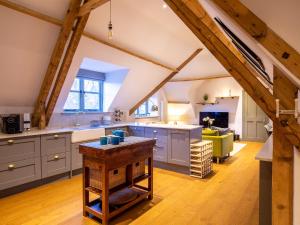 an attic kitchen with white cabinets and a table at The Hayloft in Winchcombe