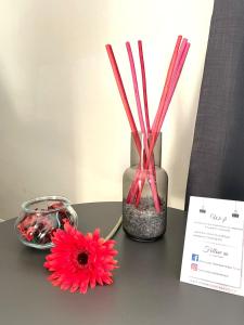 une table avec un vase avec des fleurs rouges et des bâtons dans l'établissement Best Quality Hotel Dock Milano, à Turin