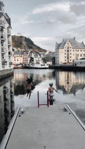 a man and a woman standing on a pier looking at the water at Hotel Brosundet in Ålesund
