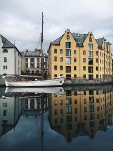 una barca seduta in acqua di fronte agli edifici di Hotel Brosundet ad Ålesund