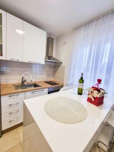 - une cuisine blanche avec une bouteille de vin sur un comptoir dans l'établissement Apartment Ane 2, à Tisno