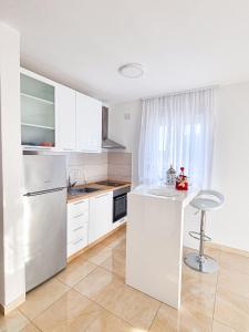 une cuisine blanche avec un comptoir et un tabouret dans l'établissement Apartment Ane 2, à Tisno